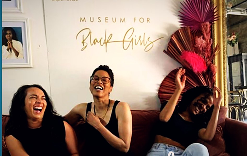 Guests laughing together on the community couch at Museum for Black Girls