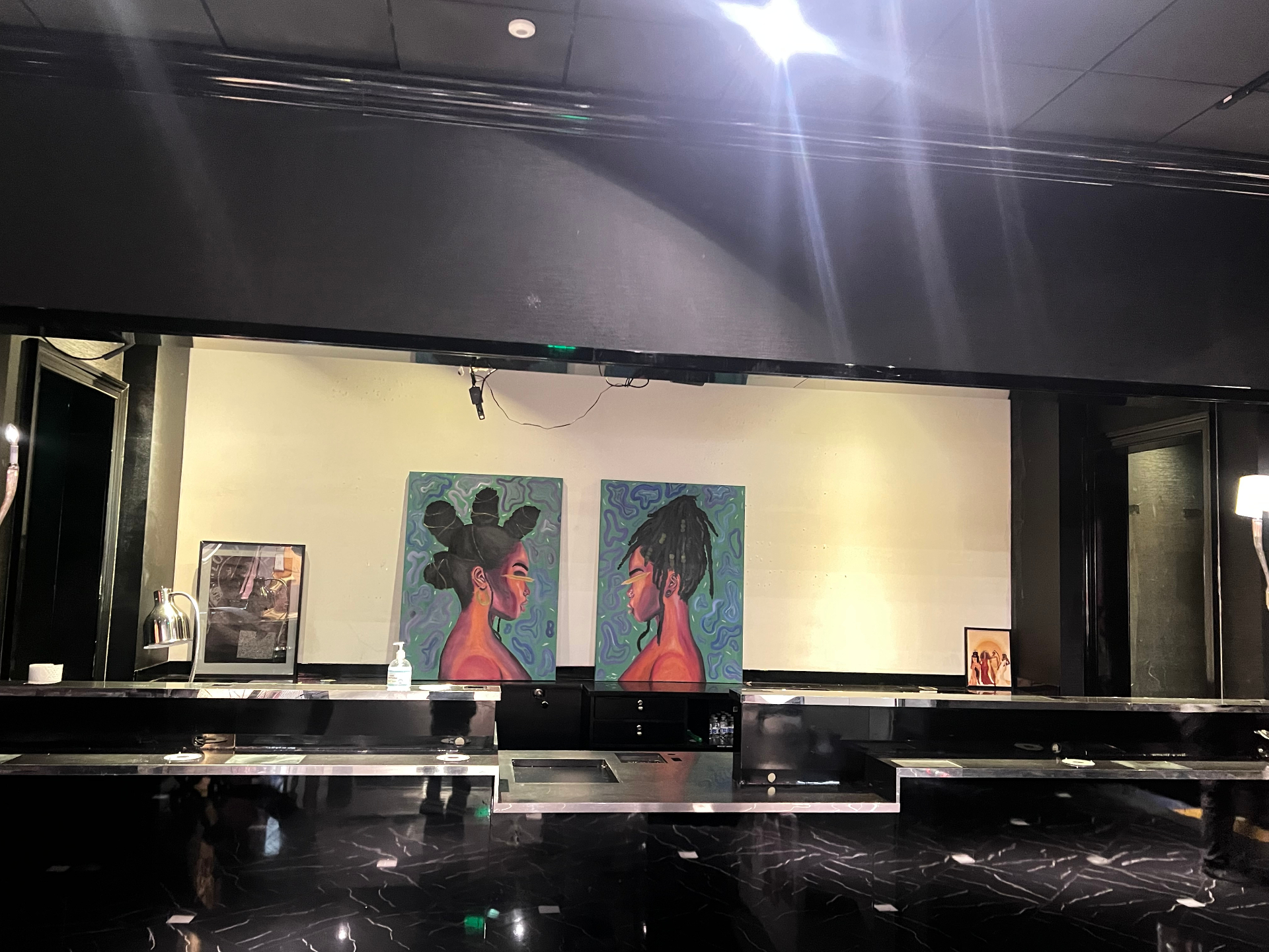 Twin portrait paintings of Black women on a moody gallery wall