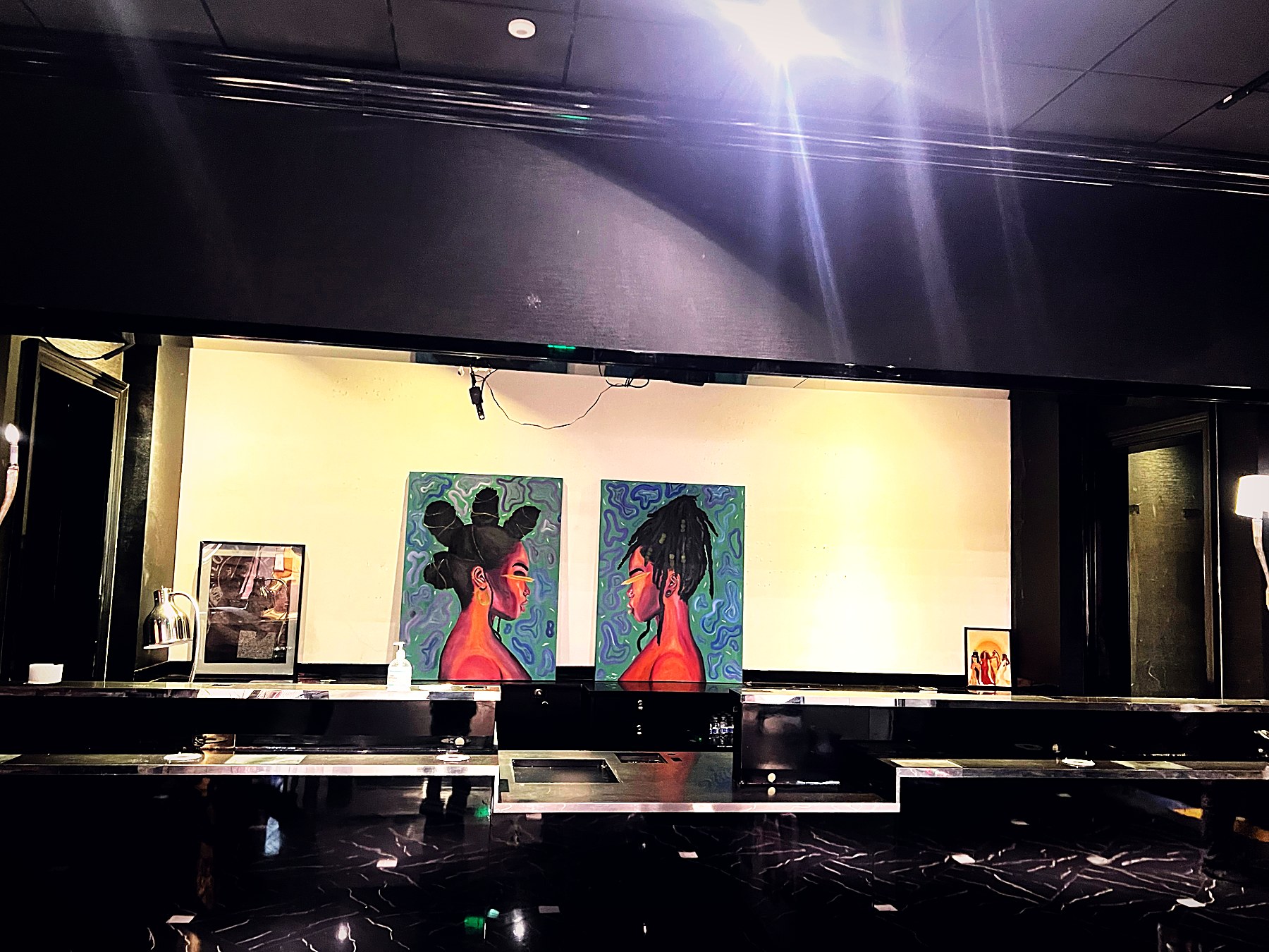 Painted portraits of Black women hung on a moody gallery wall at Museum for Black Girls
